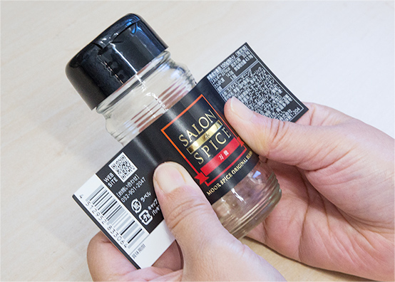 オリジナルスパイスの瓶にラベルを貼る様子